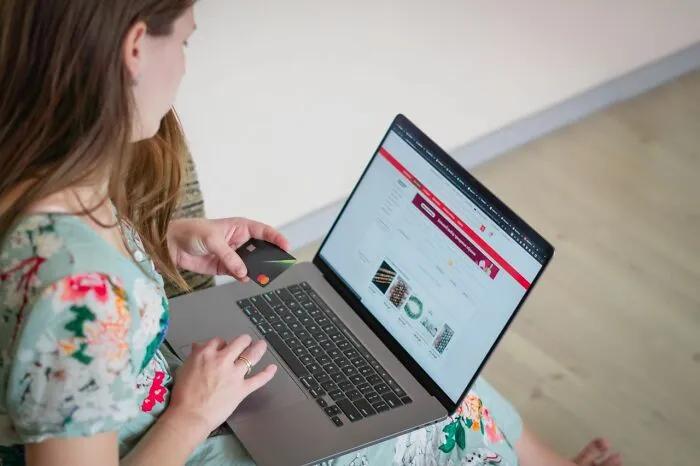 A woman holding a credit card and shopping online, illustrating clever life tricks for saving money