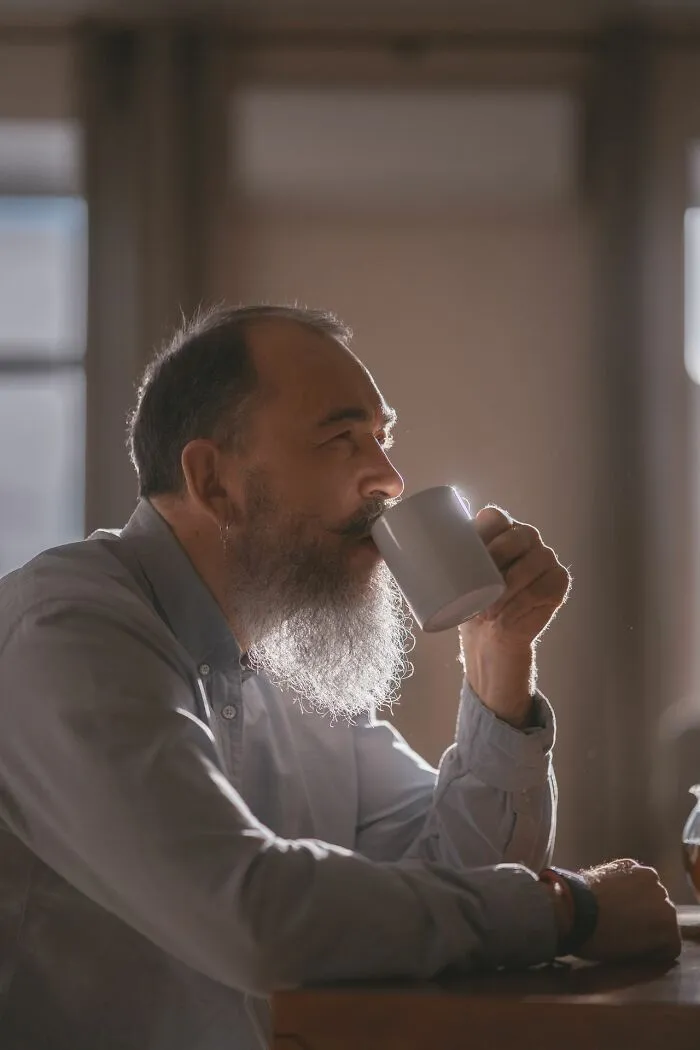 Bearded man drinking coffee at table illustrating adult reflection in Karen stories