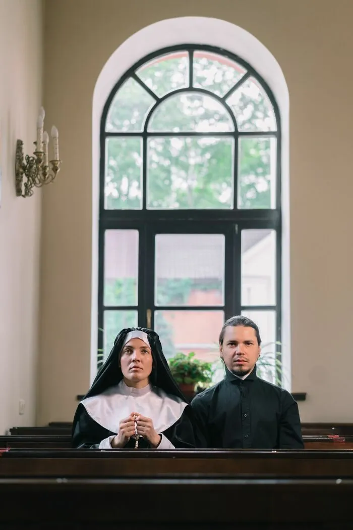 A nun and a priest sitting in church pews, hinting at wild school rumors