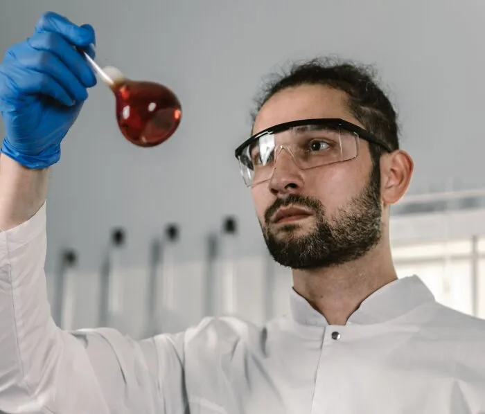 A scientist holding a glass flask carefully to avoid a costly slip-up in the lab.