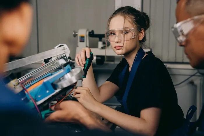 A young woman working with machinery in a workshop, illustrating dumb things professionals did on the job