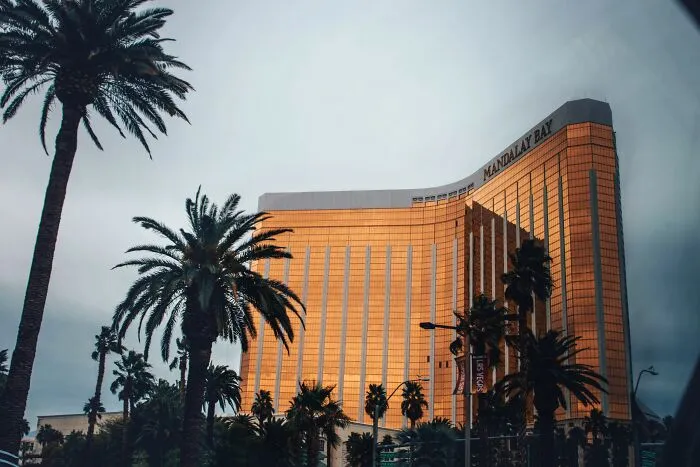 Exterior view of the Mandalay Bay hotel surrounded by palm trees, highlighting real legal rules.