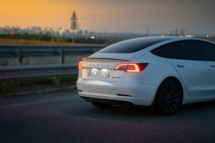 A white Tesla car parked on the roadside, showing how unethical life pro tips can help with transport