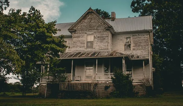 Old weathered house surrounded by trees illustrating real property laws