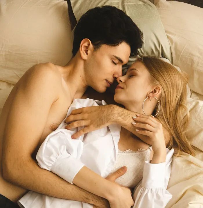 A young couple lying together in bed looking intimately at each other