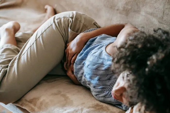 Person lying on couch holding stomach in discomfort practical life hacks