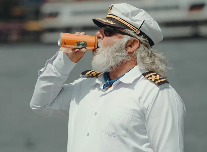 A captain drinking soda, looking relaxed before an unexpected mistake leads to a massive bill.