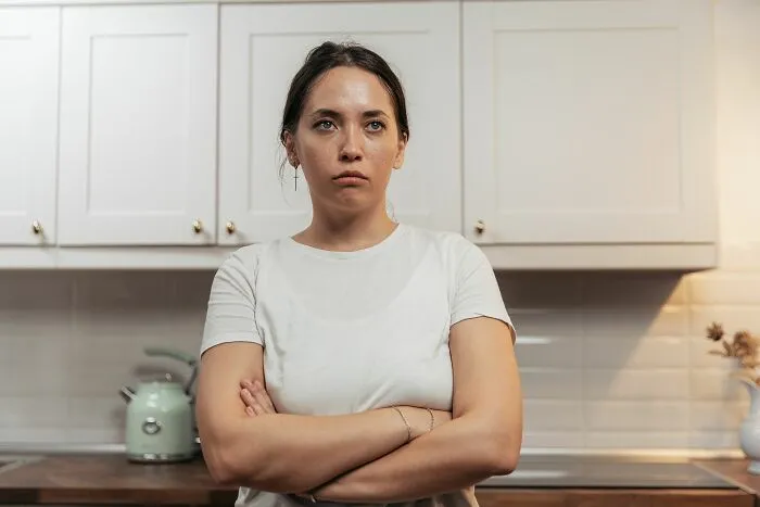 Woman in white shirt with crossed arms looking frustrated about microaggressions