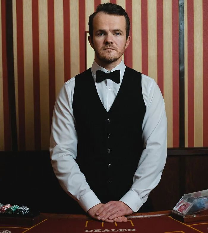 A casino dealer standing at a gaming table, showing how a slip-up in gambling can turn into a massive bill.