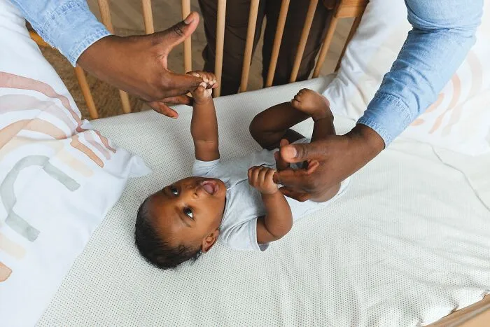Adult hands holding and playing with baby illustrating family moments amid microaggressions