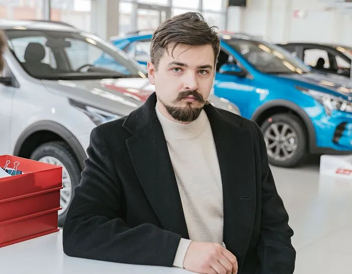 Man in a car dealership setting, reflecting on microaggressions women encounter