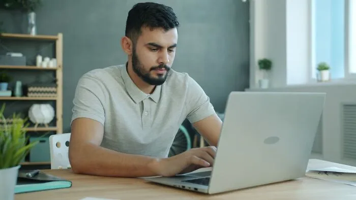 A focused man typing on a laptop, illustrating a moment from satisfying revenge stories.