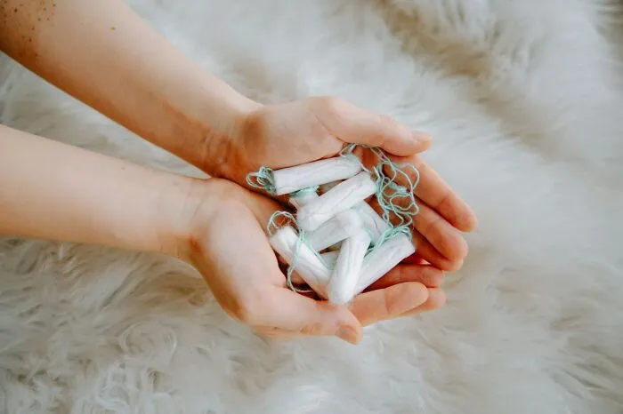Hands holding a pile of tampons, representing misconceptions about women’s bodies.