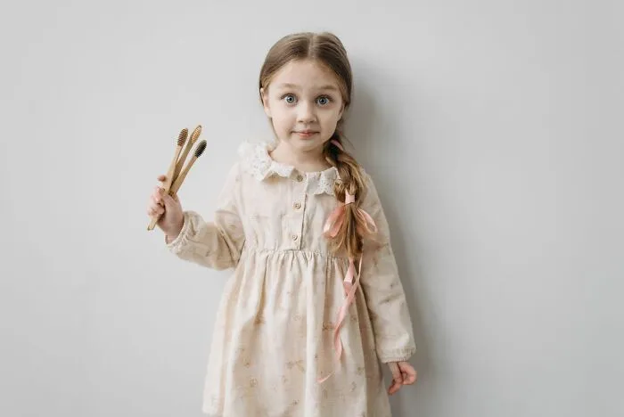 A young girl holding wooden toothbrushes received during trick-or-treating