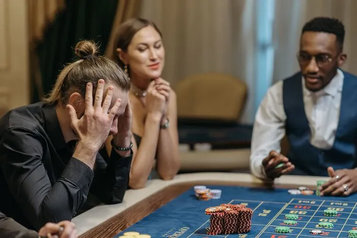 A stressed man at a casino table realizing his expensive slip-up.