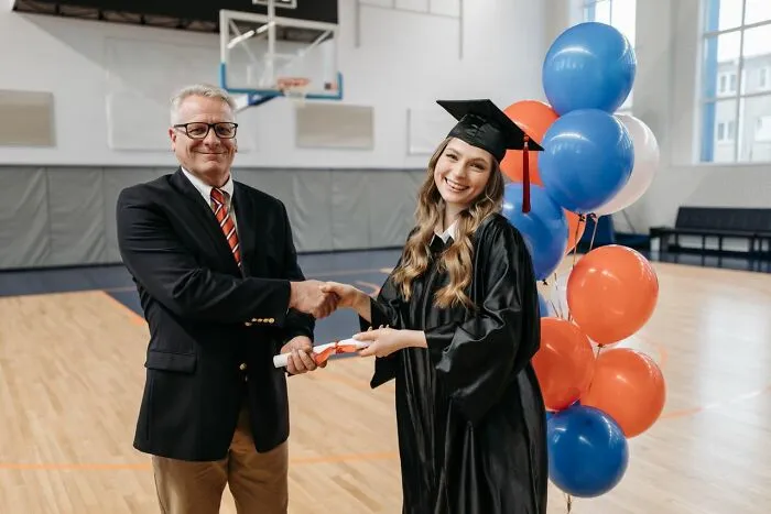 A principal shaking hands with a graduate, highlighting school rumors about graduation requirements