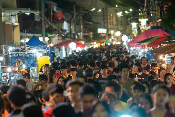 A crowded street market at night with many people. Unethical Life Pro Tips.