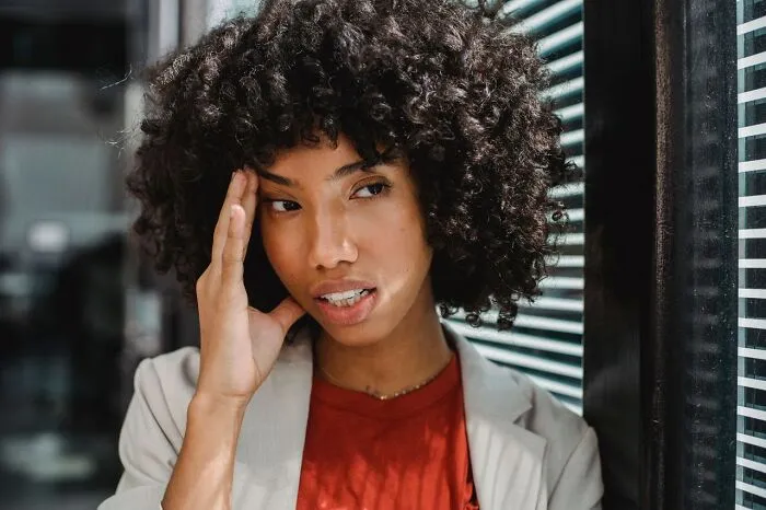 A frustrated woman touching her face, reacting to claims about women’s bodies.