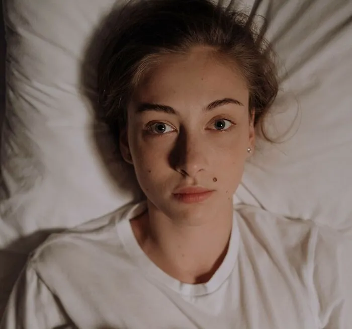 Woman lying in bed looking up pensively with deep secrets folks hold inside.