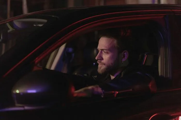 A concerned man driving his car at night, overwhelmed by an urgent feeling to leave immediately