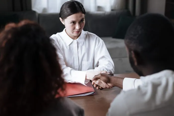 Professional woman shaking hands with clients, illustrating industry insiders in corporate settings.