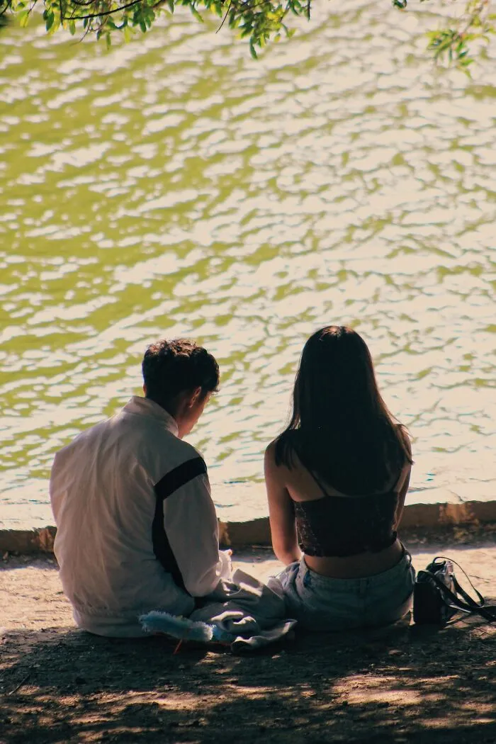 A young couple sitting by the water, evoking discussions of classic school rumors