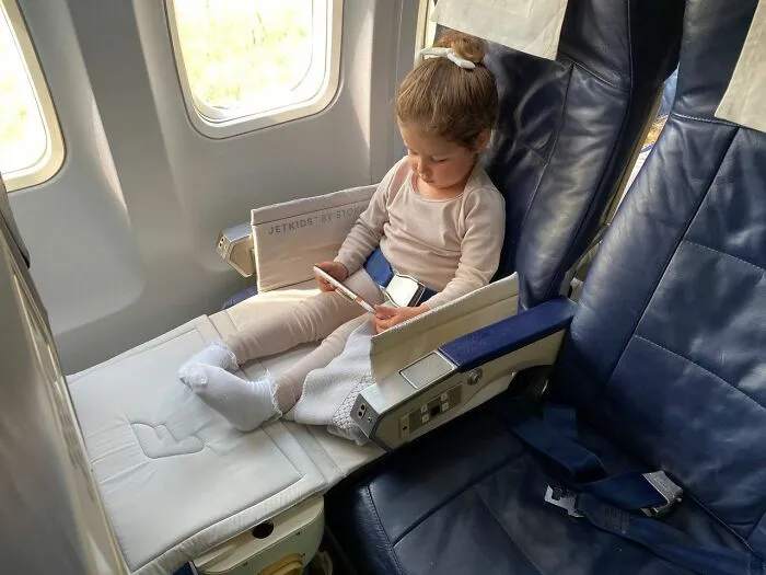 A young kid sitting in a comfortable airplane seat during family flights