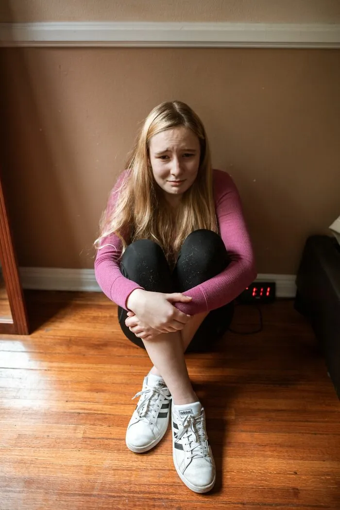 A sad student sitting on the floor, reflecting school rumors of a haunted classroom