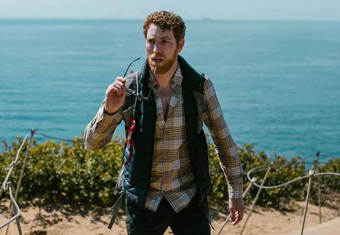 A man near the ocean taking off his glasses after a gut feeling told him something was off.