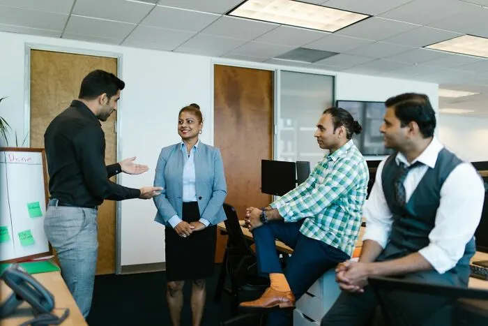 A group of colleagues in an office sharing clever life tricks during a productive team discussion.
