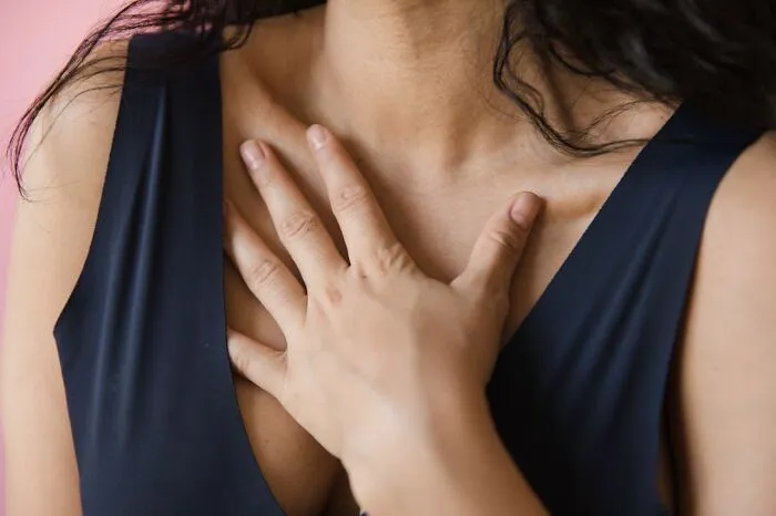 A woman resting her hand on her chest, related to myths about women’s bodies.