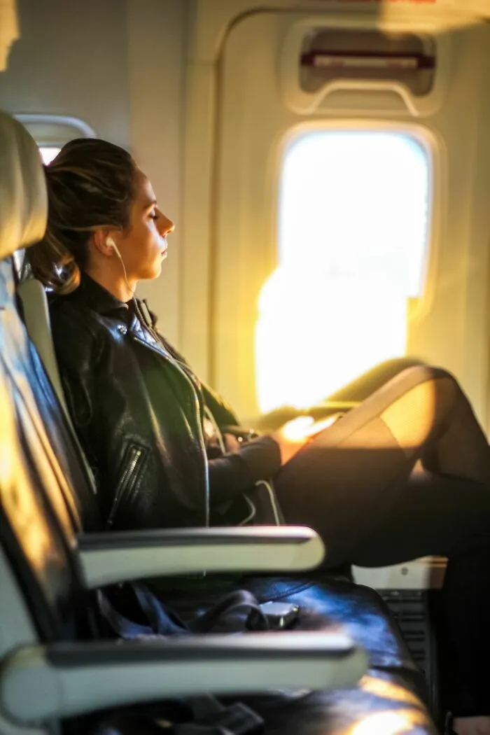 A woman wearing a black leather jacket sitting on a plane to get better seats on flights