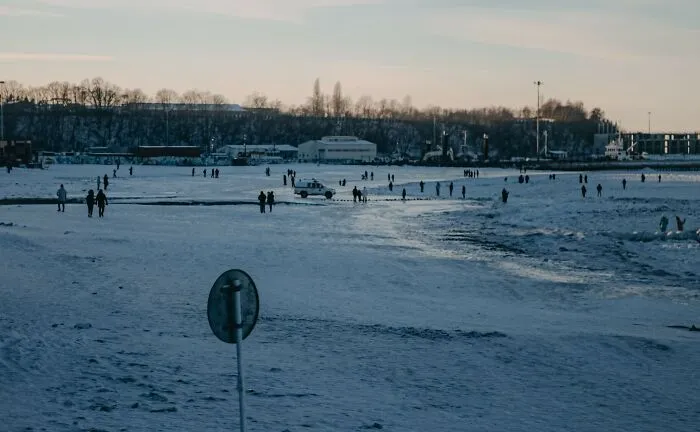 Distant view of people walking on a snowy frozen landscape subject to local laws and regulations.