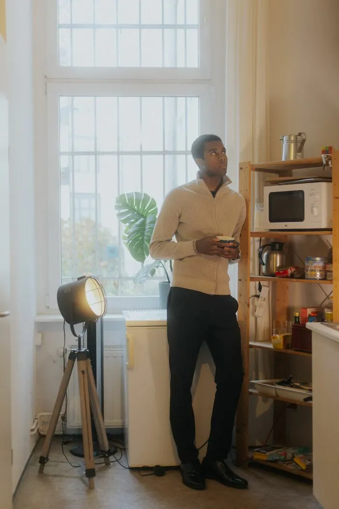 Man looking out a kitchen window, feeling an urgent, uneasy sensation to leave immediately