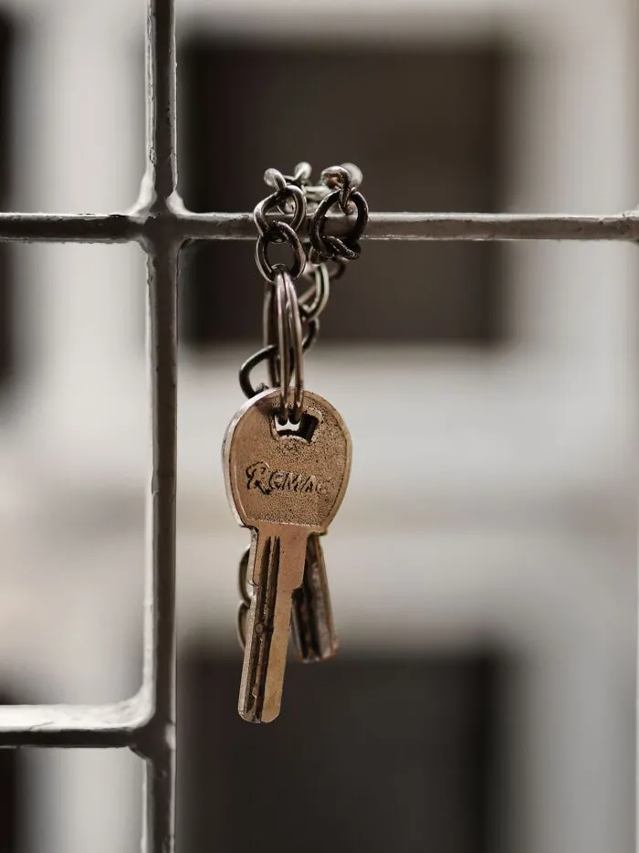 A set of keys hanging on a metal fence in a revenge story concept