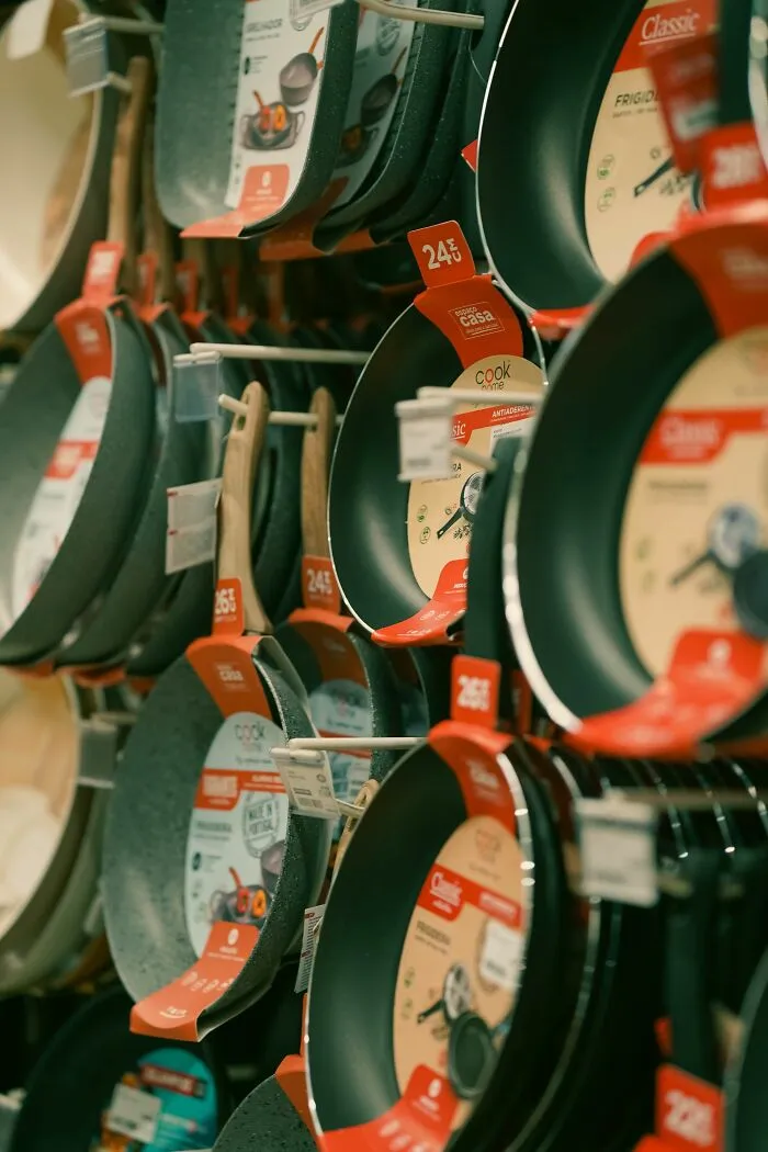 Assorted non-stick frying pans hanging on display shelves, representing companies consumers refuse to support.