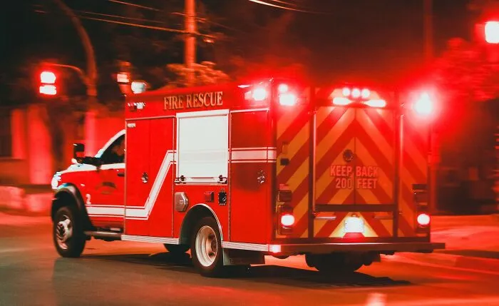 A red fire rescue vehicle speeding with emergency lights on night streets, showing chilling stories.