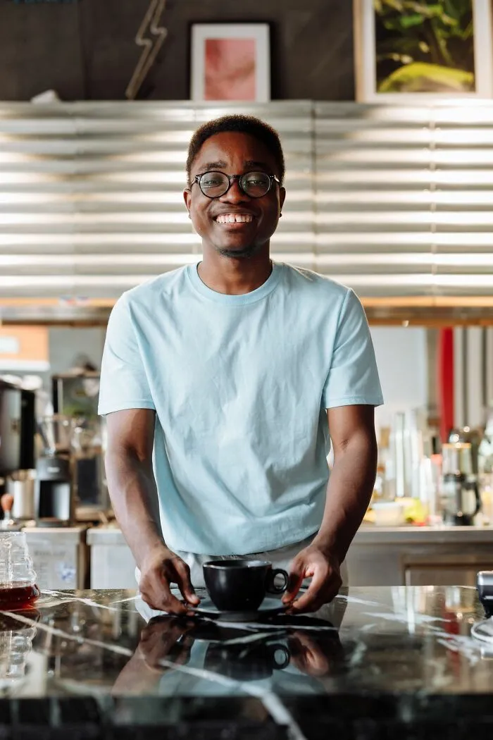 A smiling barista serving a cup of coffee highlighting clever life tricks for daily routines