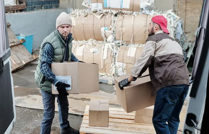 Two delivery workers loading cardboard boxes, risking a costly slip-up