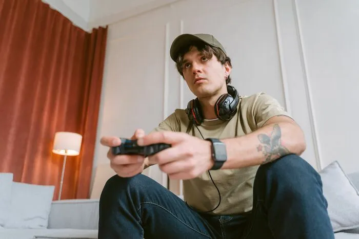 A focused young man holding a game controller, keeping hidden secrets he cannot share with anyone in real life.