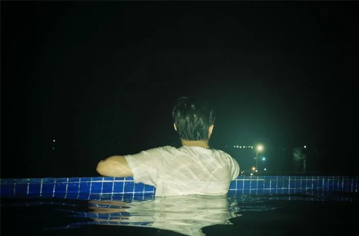 A person leaning on the edge of a pool at night, evoking chilling stories of gut feeling moments.
