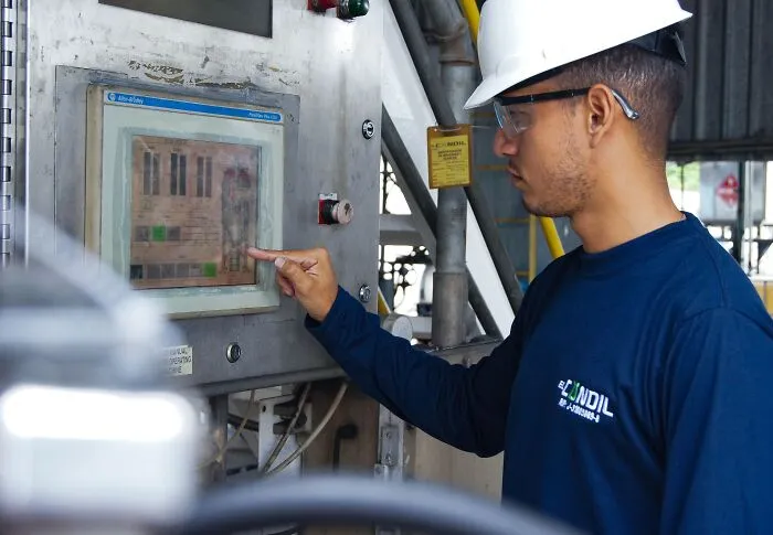 Factory worker operating a machine panel, avoiding a costly slip-up at work