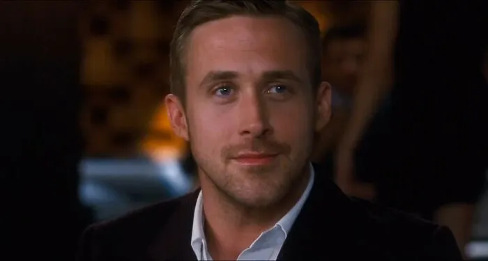 Ryan Gosling offering a gentle smile, showing positive masculinity and emotional openness.
