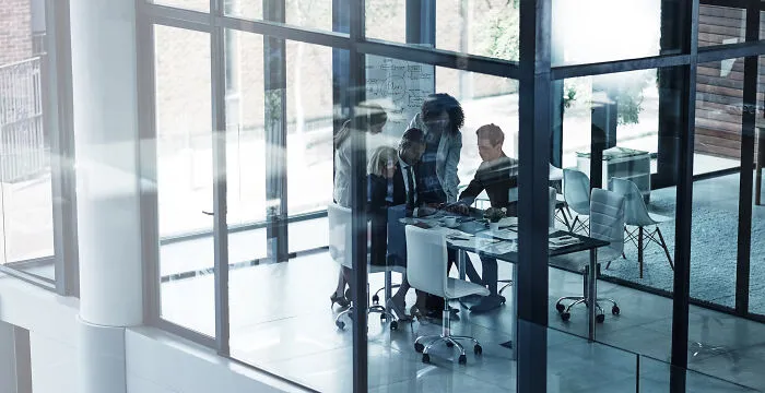 A group of corporate industry insiders meeting in a modern glass office room.