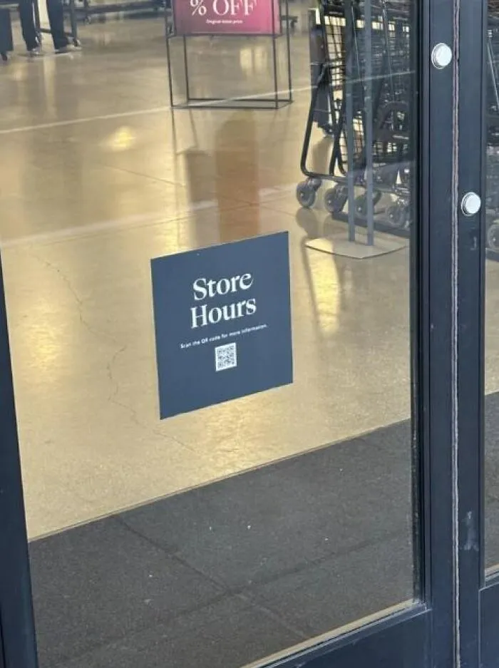 A store door with a store hours sign featuring a QR code, representing absurd signs.