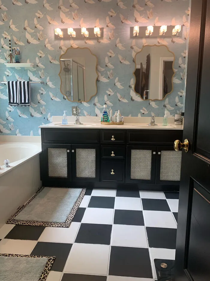Bathroom home makeover featuring blue crane wallpaper, black and white checkered floor, and dark vanity