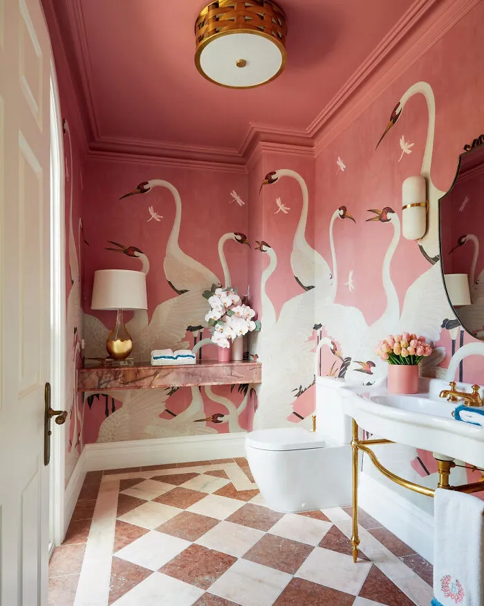 Luxury bathroom home makeover featuring pink heron wallpaper, marble tiles, and gold fixtures.