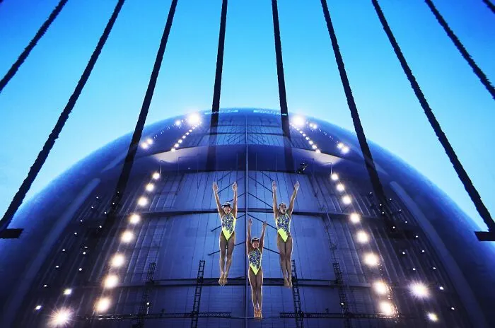 Synchronized aerial gymnasts performing with blue lighting at Siena International Photo Awards
