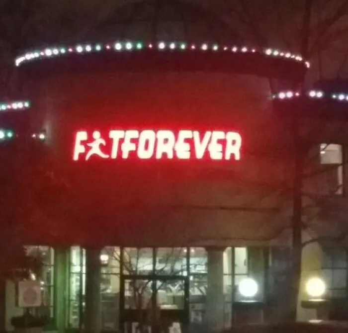 A gym sign reading FIT FOREVER illuminated to look like FAT FOREVER, showing advertising fails.