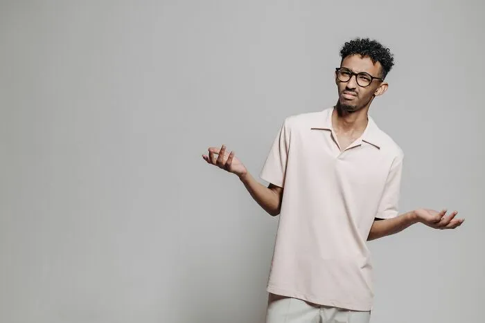 A confused young man shrugging his hands after getting fired.